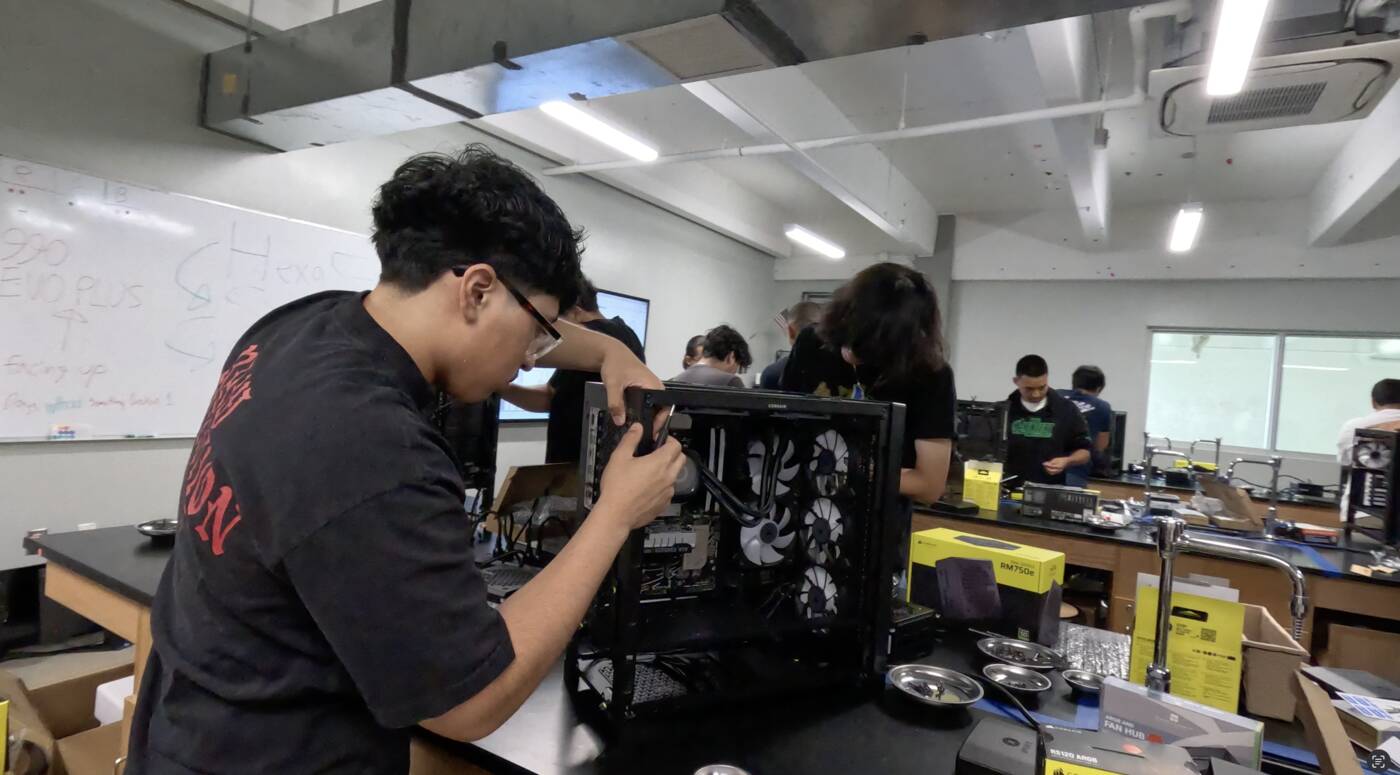 Student driving screws into his PC build in a lab full of students assembling machines